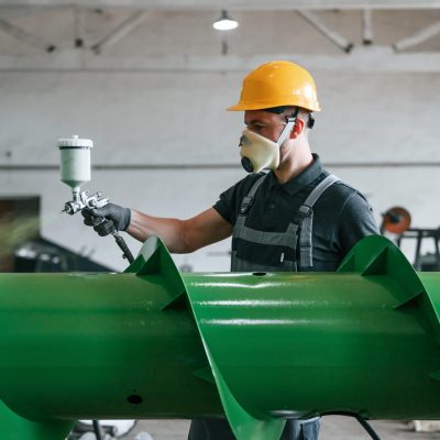 Painting details. Man in uniform is in workstation developing details of agriculture technique